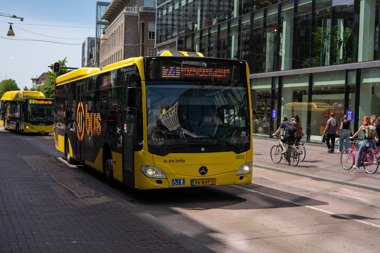 Vibrant yellow public transportation bus on a busy city street with cyclists and pedestrians.